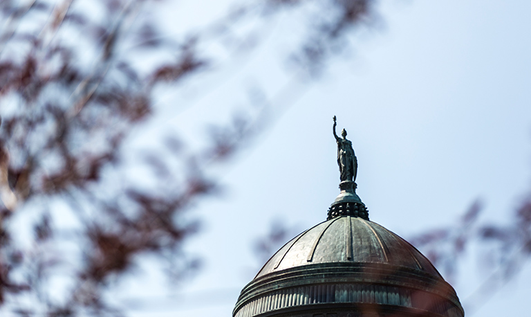A statue tops the Montana State Capitol building, looking over the city of Helena.